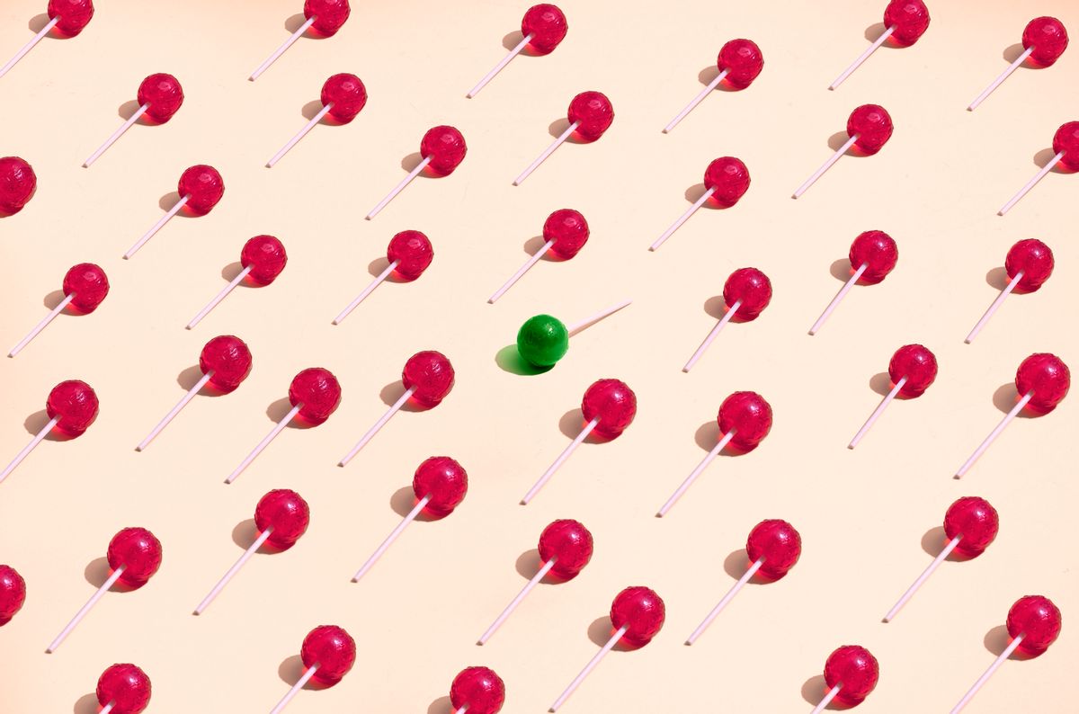large group of red lollipos placed in a pattern where a green lollipop is standing out from the crowd (Getty Images, stock)