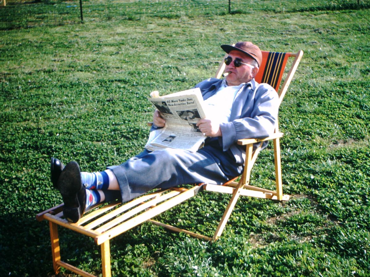 Guy relaxing in lawn chair, smoking cigar, reading newspaper. (Internet Archive/Public Domain)