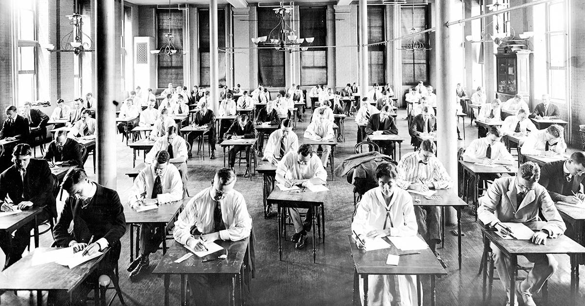 Candid photograph of students wearing suits sitting at desks taking an exam in a open room with tall windows and chandeliers at Johns Hopkins University, Baltimore, Maryland, 1950. (Photo by JHU Sheridan Libraries/Gado/Getty Images). (JHU Sheridan Libraries/Gado/Getty Images)