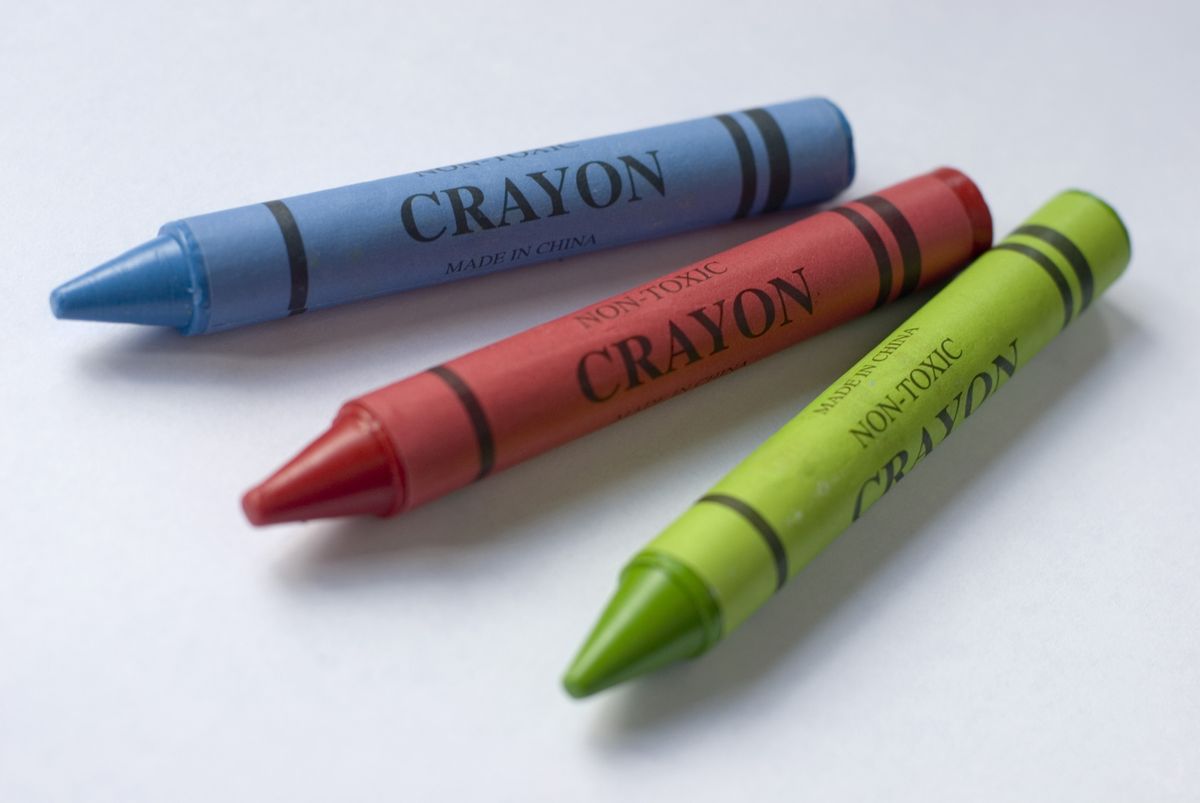 Wax crayons in primary colours of red, green and blue on a white background