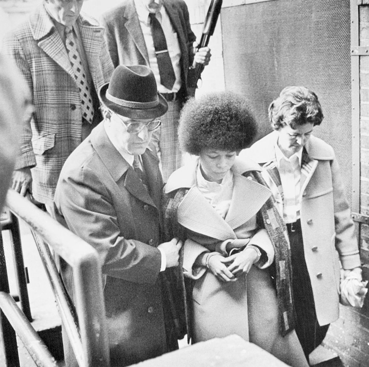 (Original Caption) New Brunswick, N.J.: Reputed black militant leader Joanna Chesimard leaves Middlesex County court April 25, escorted by County Sheriff Joseph DeMarino (light coat) after Miss Chesimard was sentenced to 26 to 33 years on various assault, weapons and robbery charges in connection with the 1973 murder of a New Jersey State trooper. Miss Chesimard is currently serving a life sentence for the murder conviction.
