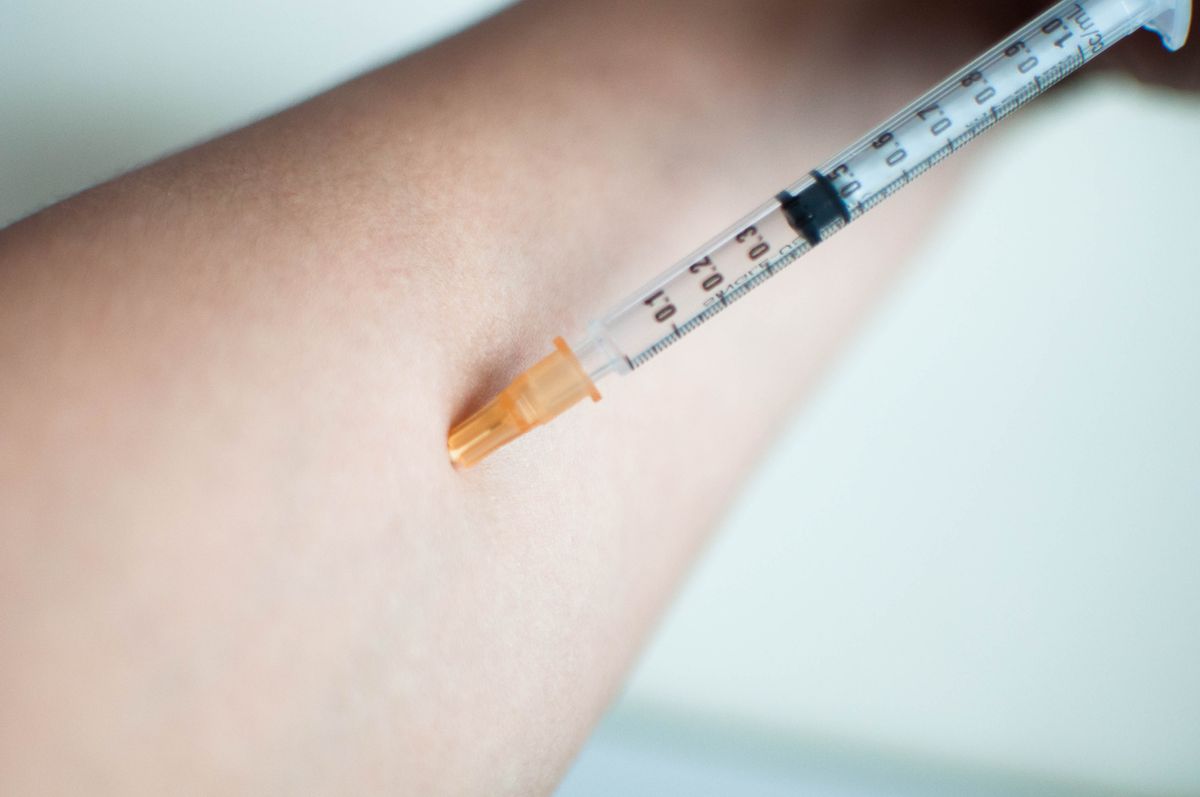 Close up of injecting a medicine on the forearm indoor against white background
