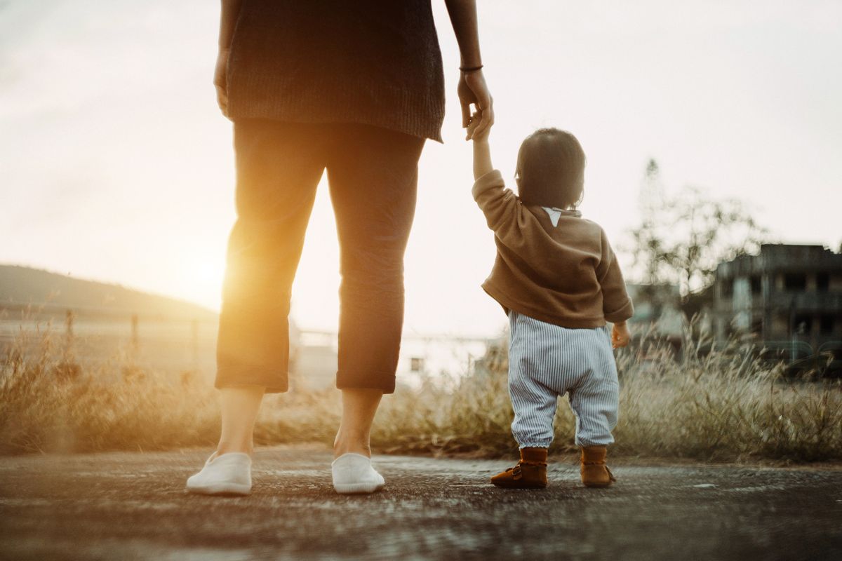 Low section of mother holding baby daughter's hand  walking in the park and enjoying the beautiful sunset (Getty Images)