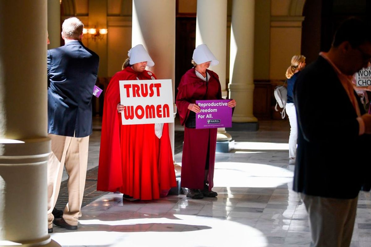 Activist Tamara Stevens (L) with the Handmaids Coalition of Georgia holds a sign as Democratic presidential candidate Sen. Kirsten Gillibrand (D-NY) addresses an event at the Georgia State Capitol to speak out against the recently passed "heartbeat" bill on May 16, 2019 in Atlanta, Georgia. - The bill, which bans abortions after a fetal heartbeat is detected around six weeks, was signed on May 15 by Alabama Governor Kay Ivey. Under the new measure, expected to come into effect in six months, performing an abortion is a crime that could land doctors in prison for up to 99 years. (Photo by John Amis / AFP)        (Photo credit should read JOHN AMIS/AFP/Getty Images) (Getty Images)