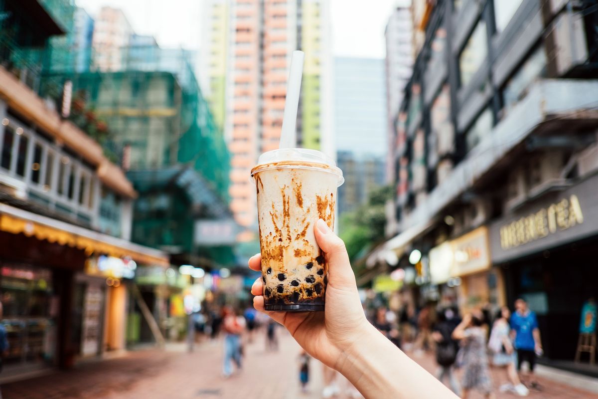 Human hand holding a bottle of iced cold bubble tea against city street in a hot summer day (Getty Images)