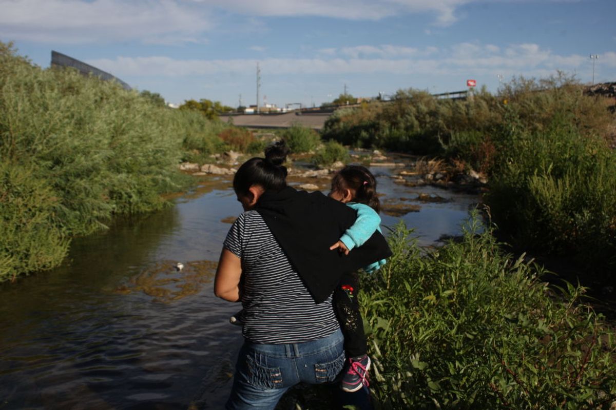 A woman on 19 May 2019 crosses the Rio Bravo, Mexico, with her son in her arms, to reach the United States surrender to border patrol agents and request asylum. Hundreds of migrants cross the Rio Bravo every day to reach the United States. (Photo by David Peinado/NurPhoto via Getty Images) (Getty Images)
