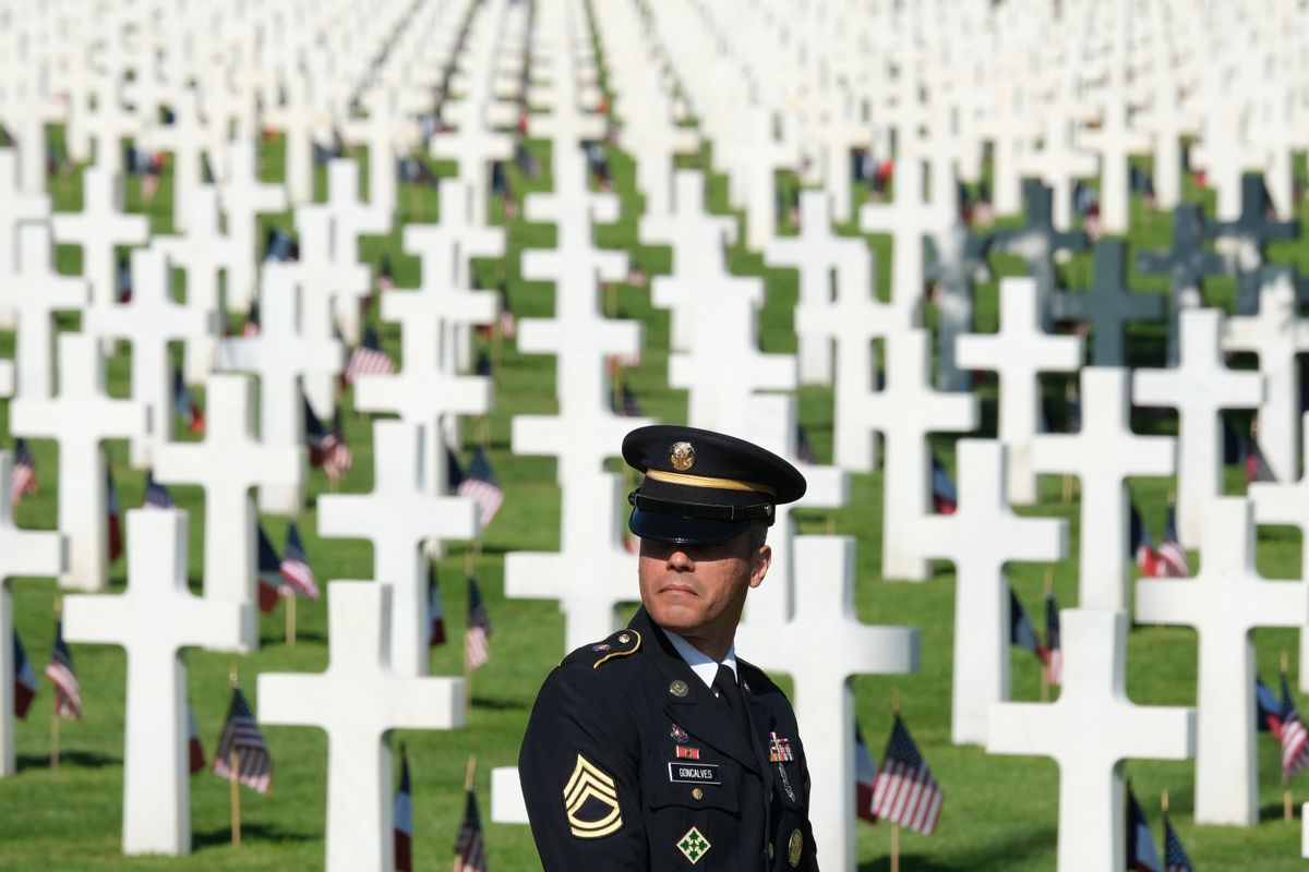 COLLEVILLE-SUR-MER, FRANCE - JUNE 06:  SFC Andre Goncalves, a member of the U.S. Army Europe band, stands among graves at Normandy American Cemetery on the 75th anniversary of the World War II Allied D-Day invasion on June 06, 2019 near Colleville-Sur-Mer, France. Veterans, families, visitors, political leaders and military personnel are gathering in Normandy to commemorate D-Day, which heralded the Allied advance towards Germany and victory about 11 months later. Normandy American Cemetery contains the graves of over 9,600 U.S. soldiers killed on D-Day and in the Battle of Normandy.  (Photo by Sean Gallup/Getty Images) (Sean Gallup/Getty Images)