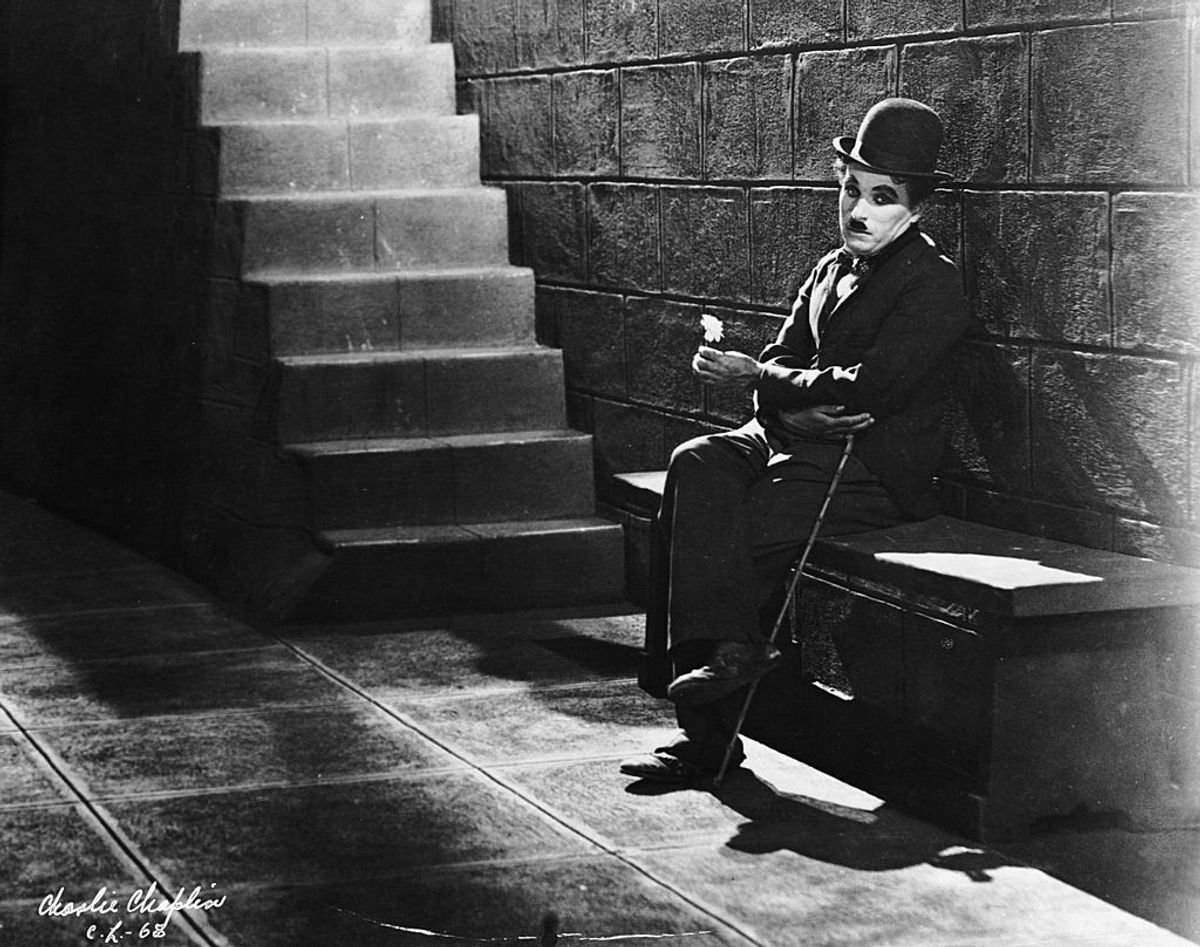 1931:  Comic actor Charlie Chaplin (1889 - 1977) sitting forlornly at the bottom of the steps in a scene from the film 'City Lights'.  (Photo via John Kobal Foundation/Getty Images) (Getty Images)