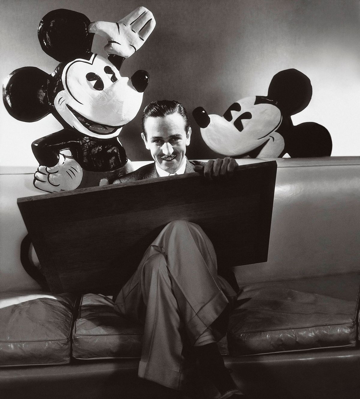 Mickey and Minnie Mouse creator Walt Disney seated with open cartoon folio and representations of his creation Mickey and Minnie behind. (Photo by Edward Steichen/Condé Nast via Getty Images) (Edward Steichen/Condé Nast via Getty Images)
