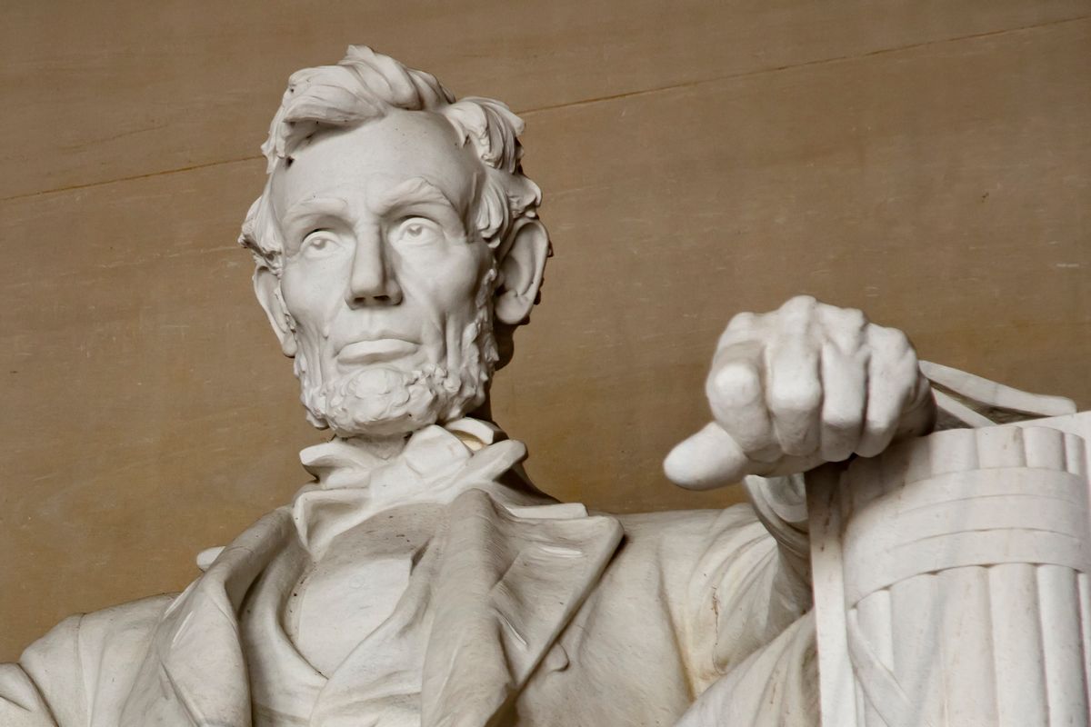Close up image of the Abraham Lincoln seated statue at the Lincoln Memorial in Washington DC. The image is focused on Abe's face, and has little more besides his chest and his left arm and hand which are resting on the arm of his chair. (Getty Images)