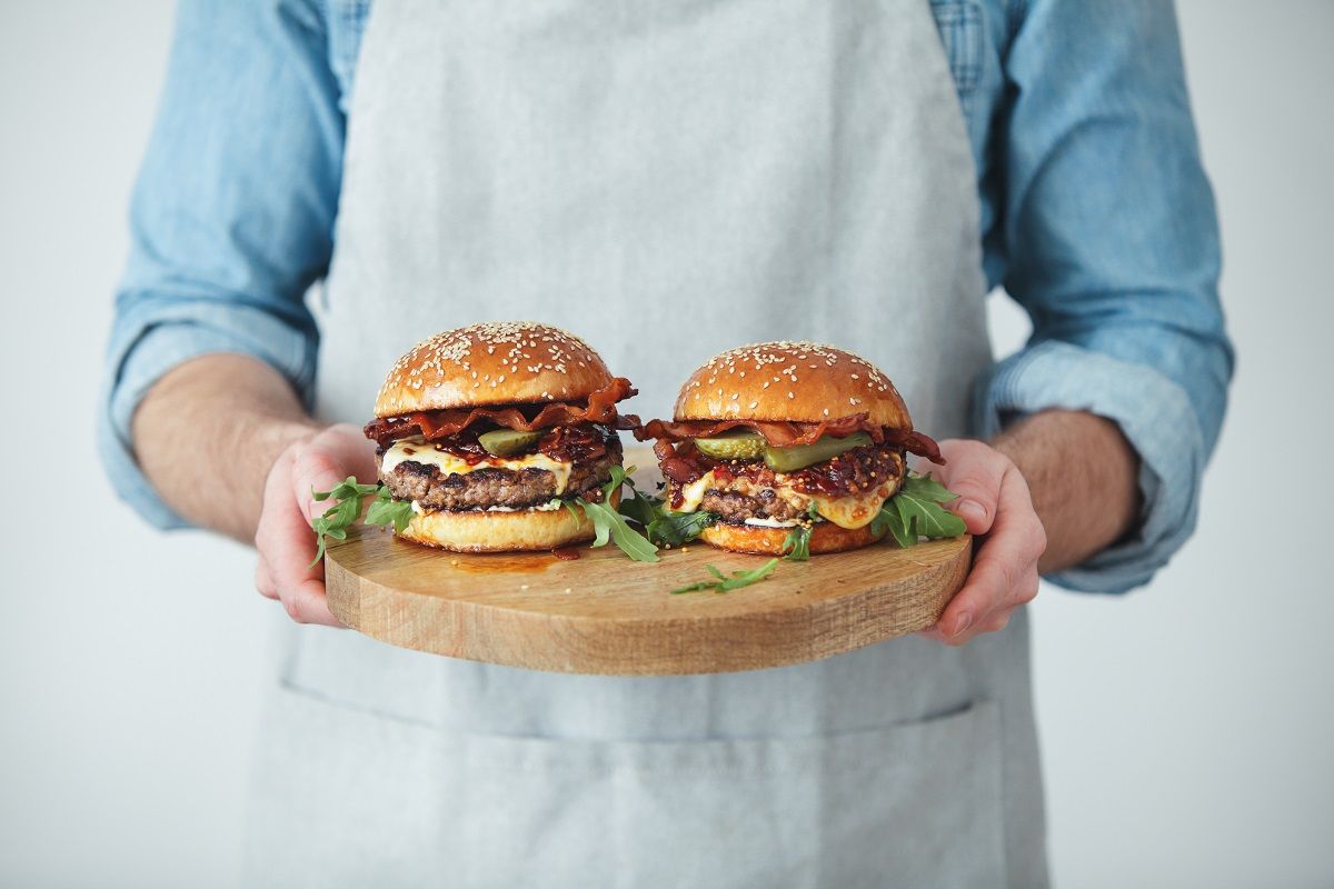 Man holding homemade angus beef burgers with bacon whisky jam - stock photo ( Eugene Mymrin / Getty Images)