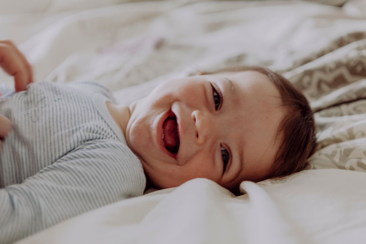 Happy baby, lying on bed, laughing (Getty Images/Stock photo)