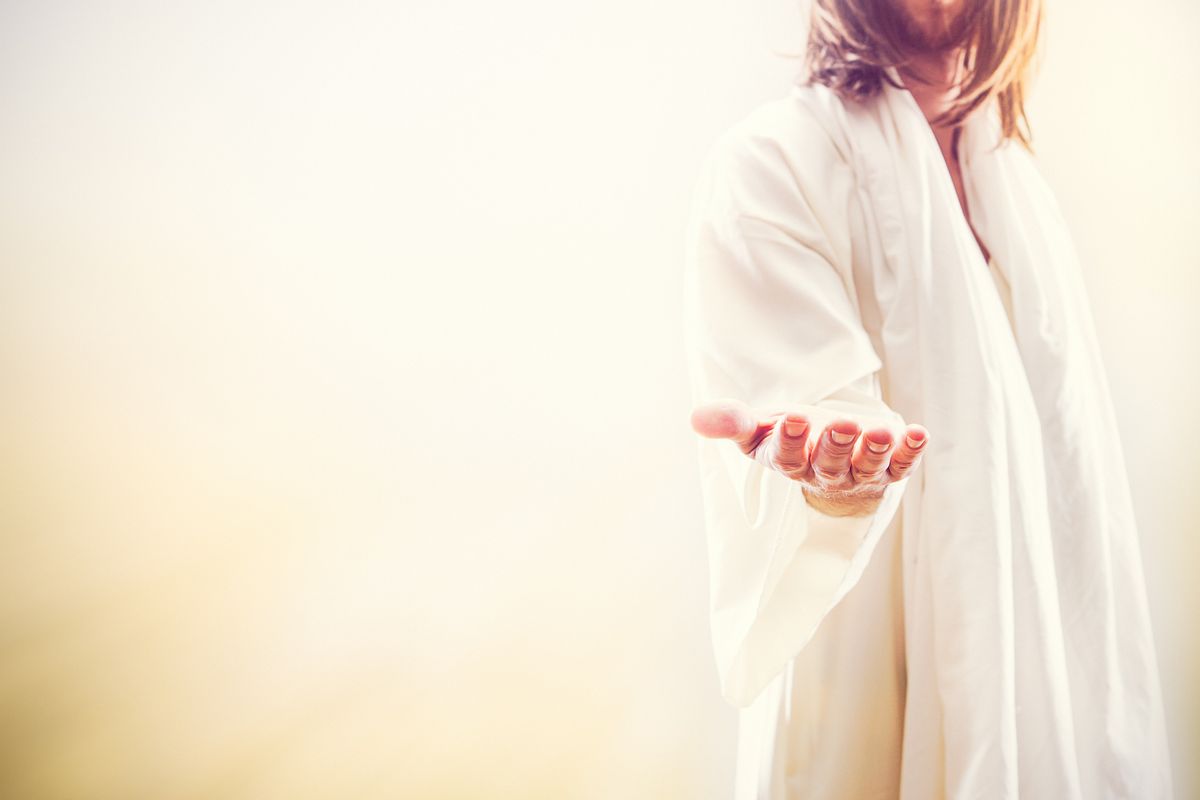 A representation of Jesus Christ following the resurrection in a heaven like setting, extending his hand with the invitation of new life.  His face is obscured, and bright golden light shines around him. A fitting image for Christ rising from the dead as celebrated on Easter Sunday. Horizontal image with copy space. (Getty Images/Stock photo)