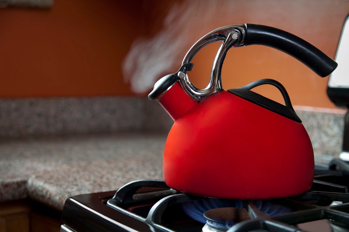 A red shiny teapot in a kitchen boils water. (Getty Images / JasonDoiy)