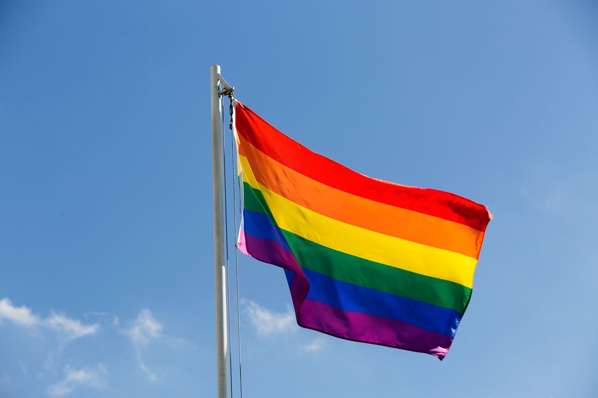 Rainbow flag on a flagpole in front of blue sky