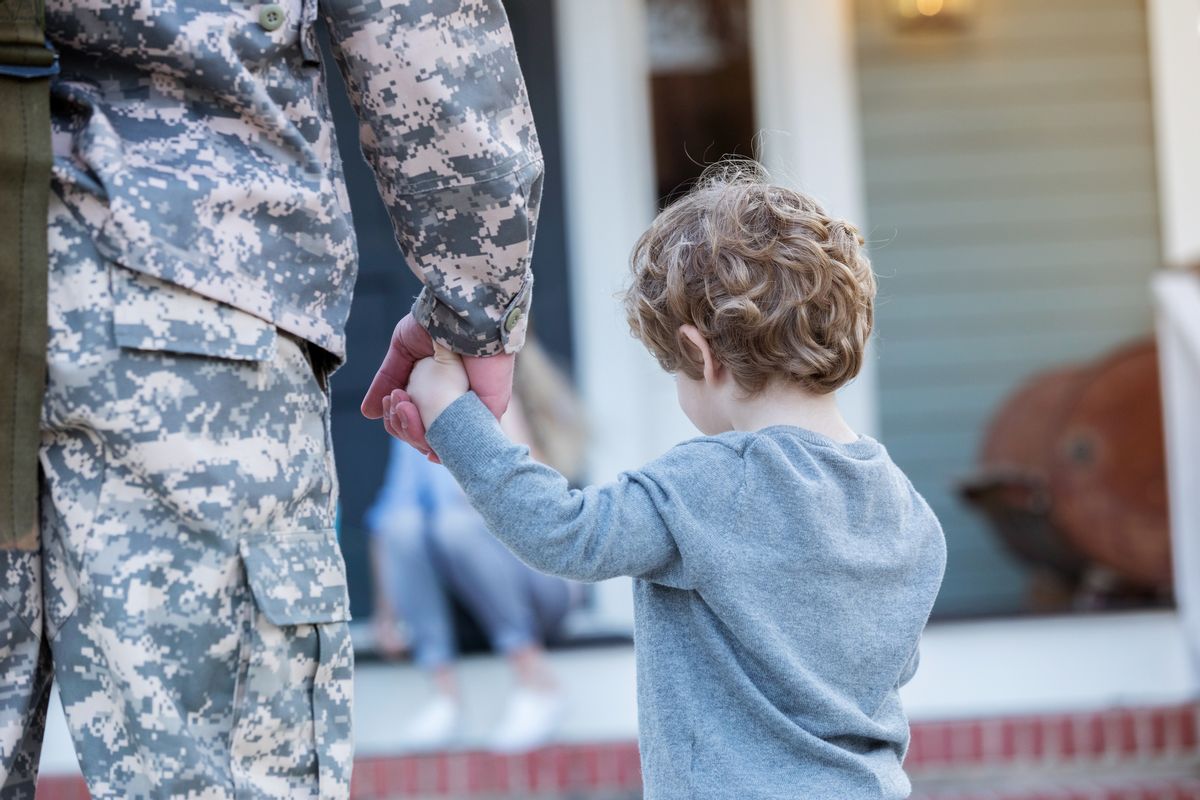 Rear view of a military dad walking hand in hand with his young son. The dad has just returned home from military assignment. (Getty Images/Stock photo)