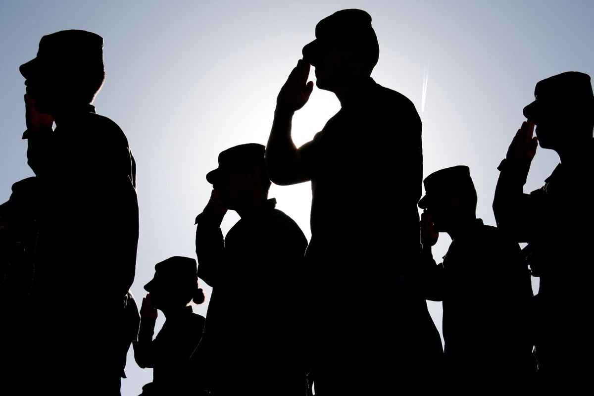 Several soldiers salute the flag at sunset during a military exercise. Army, Marines and Air Force were represented at the ceremony. (Getty Images)