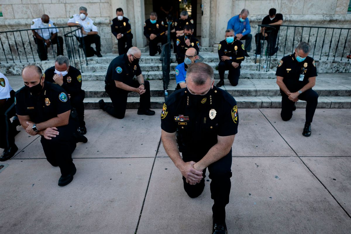 TOPSHOT - Police officers kneel during a rally in Coral Gables, Florida on May 30, 2020 in response to the recent death of George Floyd, an unarmed black man who died while being arrested and pinned to the ground by a Minneapolis police officer. - Clashes broke out and major cities imposed curfews as America began another night of unrest Saturday with angry demonstrators ignoring warnings from President Donald Trump that his government would stop violent protests over police brutality "cold." (Photo by Eva Marie UZCATEGUI / AFP) (Photo by EVA MARIE UZCATEGUI/AFP via Getty Images) (EVA MARIE UZCATEGUI/AFP via Getty Images)