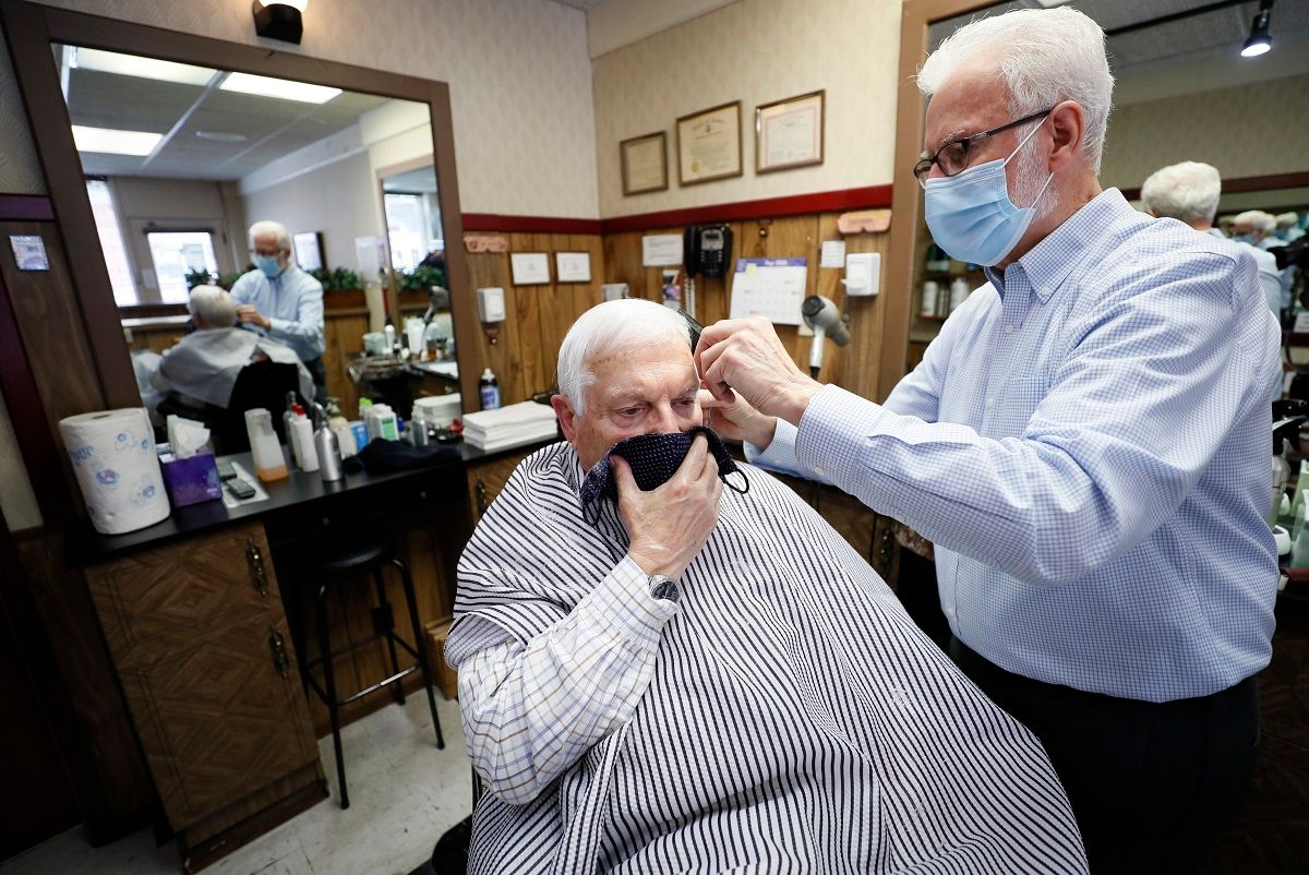 FILE - In this May 15, 2020 file photo, barber Lannie Hale cuts Bob Mitchell's hair at his Waveland Barber Stylist shop in Des Moines, Iowa.  With more businesses across the country easing back to life, the new challenge will be how to keep workers safe during the pandemic. From temperature checks, contact tracing, social distancing and staggered schedules, a variety of new protocols are being implemented. (AP Photo/Charlie Neibergall) (AP Photo / Charlie Neibergall)
