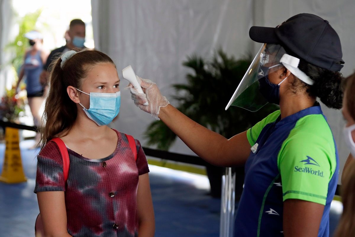 A guest has her temperature checked before entering SeaWorld as it reopens with new safety measures in place because of the coronavirus pandemic, Thursday, June 11, 2020, in Orlando, Fla. The park had been closed since mid-March to stop the spread of the new coronavirus. (AP Photo/John Raoux) (AP Photo / John Raoux)