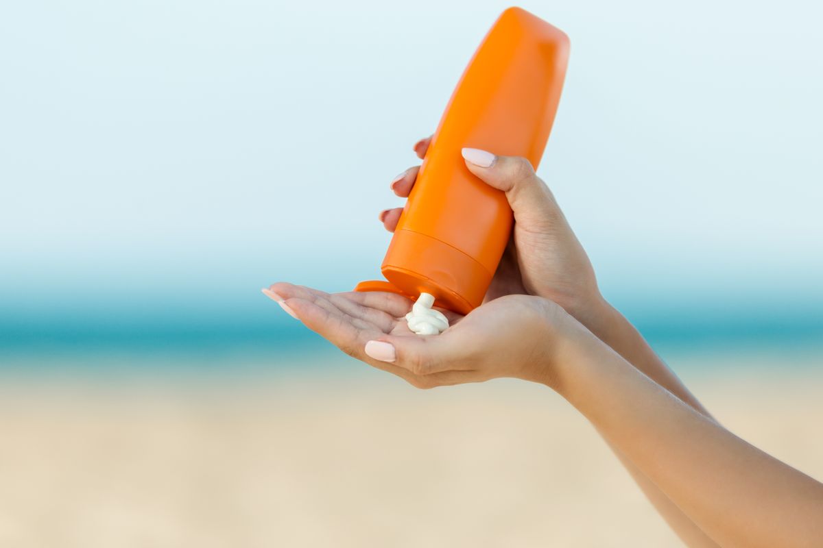 Woman hand apply sunscreen on the beach (bymuratdeniz)