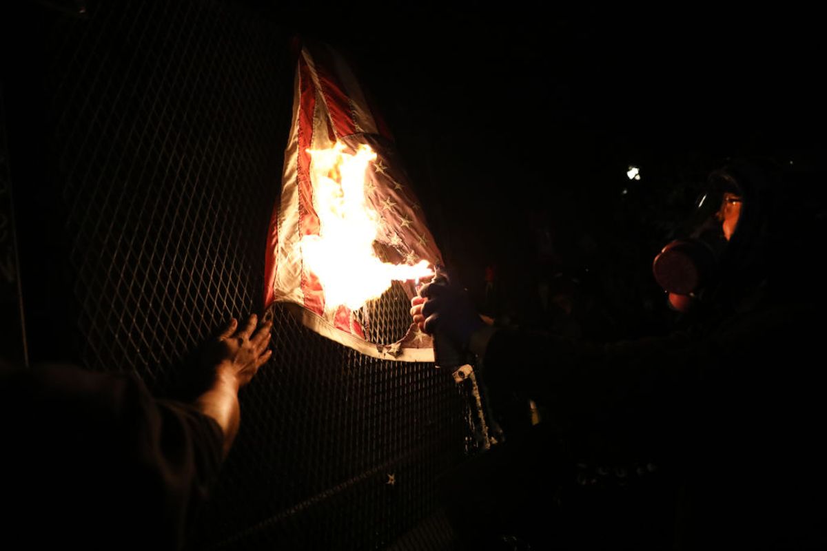 PORTLAND, OREGON - JULY 25: An American Flag is burned as protesters gather in front of the Mark O. Hatfield federal courthouse in downtown Portland as the city experiences another night of unrest on July 25, 2020 in Portland, Oregon. For over 55 straight nights, protesters in downtown Portland have faced off in often violent clashes with the Portland Police Bureau and, more recently, federal officers. The demonstrations began to honor the life of George Floyd and other black Americans killed by law enforcement and have intensified as the Trump administration called in the federal officers. (Photo by Spencer Platt/Getty Images) (Spencer Platt/Getty Images)