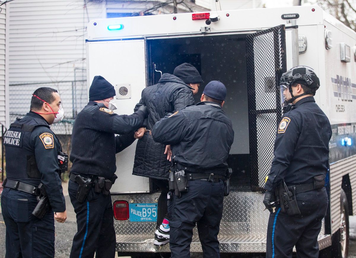 CHELSEA, MA - APRIL 9: Masked officers of the Chelsea Police Department help a suspect into the back of a "paddy wagon" on April 9, 2020 in Chelsea, MA.  Due to the COVID-19 epidemic, suspects are no longer being placed in the back of officers cruisers when placed under arrest to limit the risk of exposing officers or suspects to the Coronavirus. (Photo by Blake Nissen for The Boston Globe via Getty Images) (Blake Nissen for The Boston Globe via Getty Images)