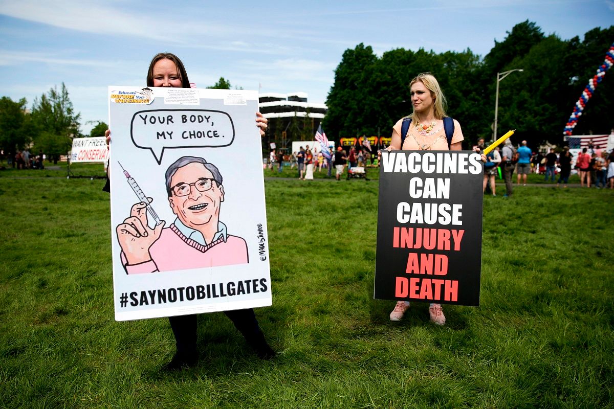 Two women hold anti-vaccination signs during a protest against Governor Jay Inslee's stay-at-home order outside the State Capitol in Olympia, Washington on May 9, 2020. - The Washington State Patrol estimates about 1,500 people rallied against Governor Jay Inslees stay-at-home order. (Photo by Jason Redmond / AFP) (Photo by JASON REDMOND/AFP via Getty Images) (Jason Redmond / Getty Images)