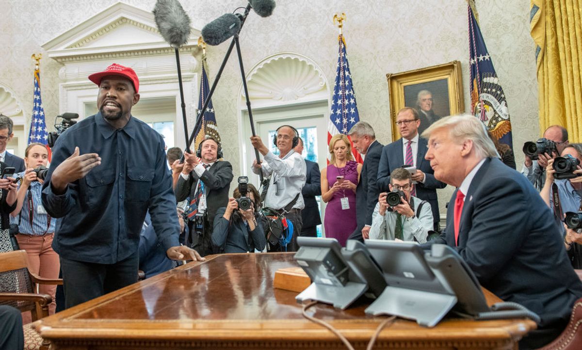 Surrounded by members of the press and others, American rapper and producer Kanye West stands as he talks with real estate developer and US President Donald Trump in the White House's Oval Office, Washington DC, October 11, 2018. West wears a red baseball cap that reads 'Make America Great Again,' Trump's campaign slogan. (Photo by Ron Sachs/Consolidated News Pictures/Getty Images) (Ron Sachs/Consolidated News Pictures/Getty Images)