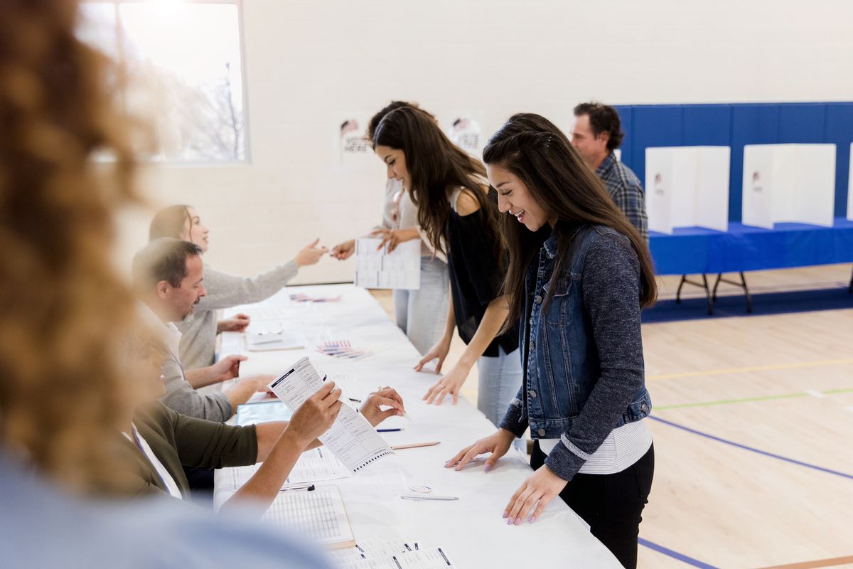 Mid adult women stand in a row to sign up to vote while the polling place volunteers help them. (Getty Images/Stock photo)