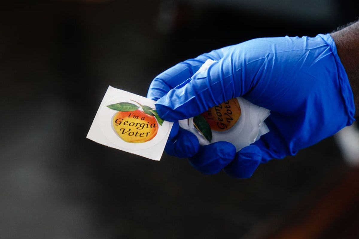 ATLANTA, GA - JUNE 09: A polling place worker holds an "I'm a Georgia Voter" sticker to hand to a voter on June 9, 2020 in Atlanta, Georgia. Georgia, West Virginia, South Carolina, North Dakota, and Nevada are holding primaries amid the coroanvirus pandemic (Photo by  Elijah Nouvelage/Getty Images) (Elijah Nouvelage/Getty Images)