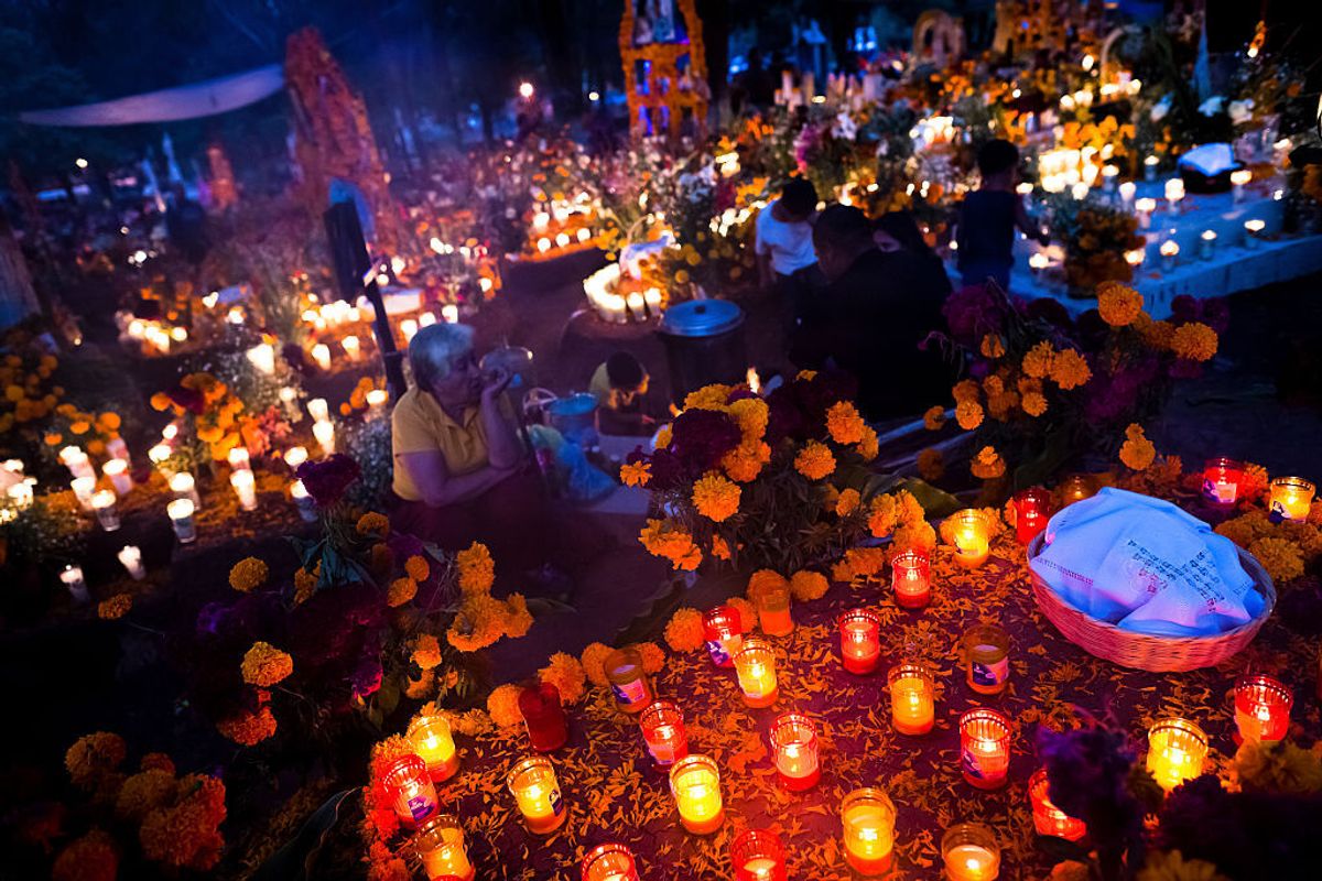 TZINTZUNTZAN, MEXICO - NOVEMBER 02: Mexican family members light candles and pray at the cemetery to honor their deceased relatives  during the Day of the Dead celebration on November 02, 2014 in Tzintzuntzan, Mexico.  Day of the Dead is a syncretic religious holiday, celebrated throughout Mexico, combining the death venaration rituals of the ancient Aztec culture with the Catholic practice. Based on the belief that the souls of the departed may come back to this world on that day, people gather on the gravesites praying, drinking and playing music, to joyfully remember friends or family members who have died and to support their souls on the spiritual journey. (Photo by Jan Sochor/Latincontent/Getty Images) (Jan Sochor / Getty Images)