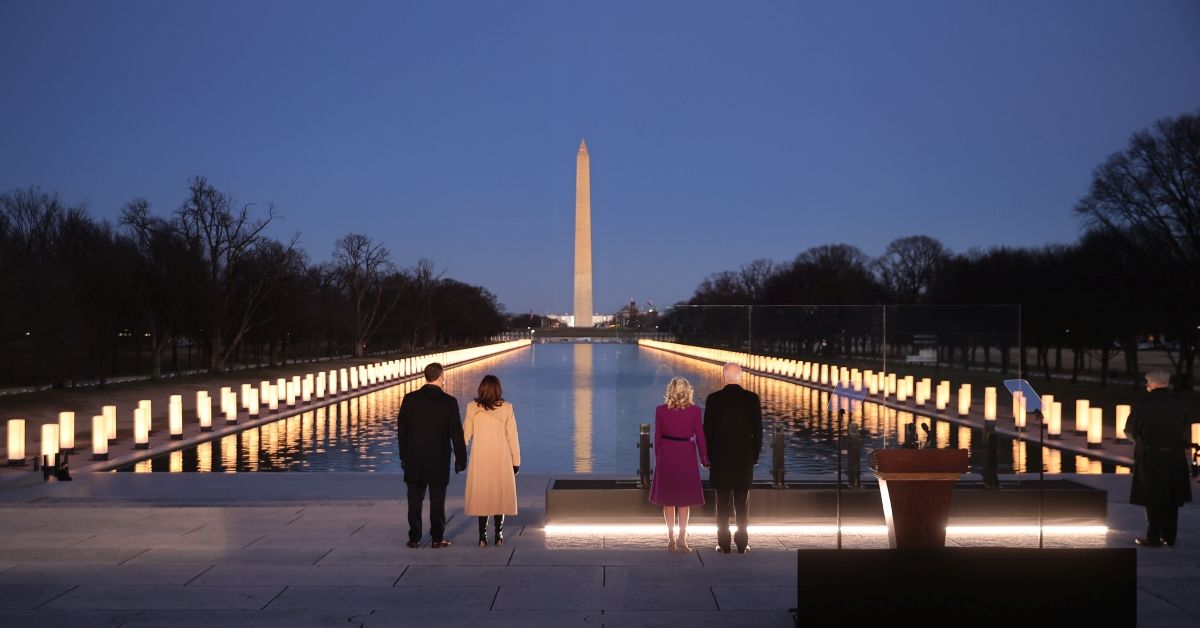 WASHINGTON, DC - JANUARY 19:  (L-R) Douglas Emhoff, U.S. Vice President-elect Kamala Harris, Dr. Jill Biden and U.S. President-elect Joe Biden look down the National Mall as lamps are lit  to honor the nearly 400,000 American victims of the coronavirus pandemic at the Lincoln Memorial Reflecting Pool January 19, 2021 in Washington, DC. As the nation's capital has become a fortress city of roadblocks, barricades and 20,000 National Guard troops due to heightened security around Biden's inauguration, 200,000 small flags were installed on the National Mall to honor the nearly 400,000 Americans killed by COVID-19. (Photo by Chip Somodevilla/Getty Images) (Chip Somodevilla/Getty Images)