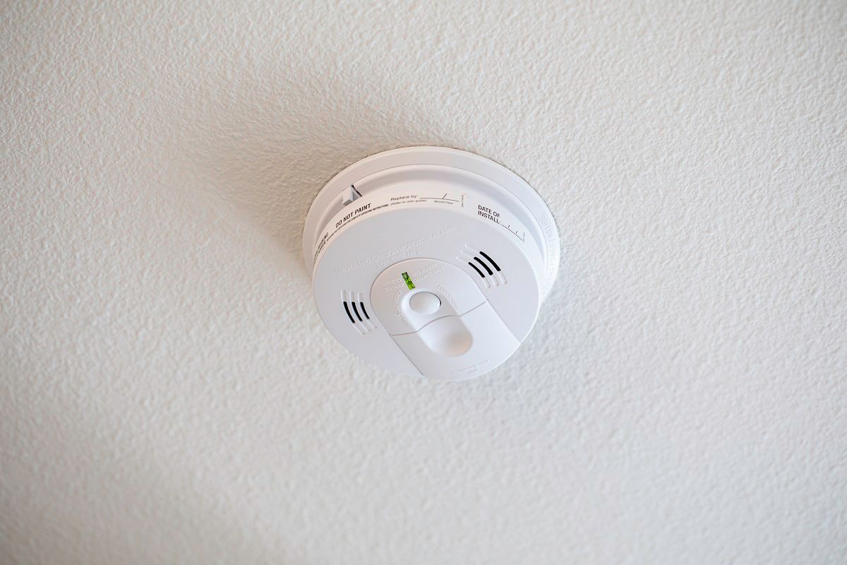 Carbon monoxide and smoke detector on a white ceiling (Garrett Aitken/iStock via Getty Images)