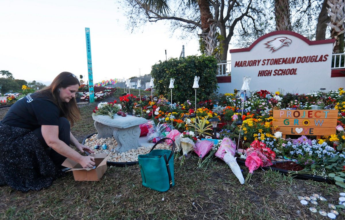 FILE - In this Feb. 14, 2019, file photo, Suzanne Devine Clark, an art teacher at Deerfield Beach Elementary School, places painted stones at a memorial outside Marjory Stoneman Douglas High School during the firstr anniversary of the school shooting in Parkland, Fla. It’s been more than 1,000 days since a gunman with an AR-15 rifle burst into a Florida high school, killing 17 people and wounding 17 others. And yet, with Valentine’s Day on Sunday, Feb. 14, 2021, marking the three-year milestone, Nikolas Cruz’s death penalty trial is in limbo. (AP Photo/Wilfredo Lee, File) (AP Photo/Wilfredo Lee)
