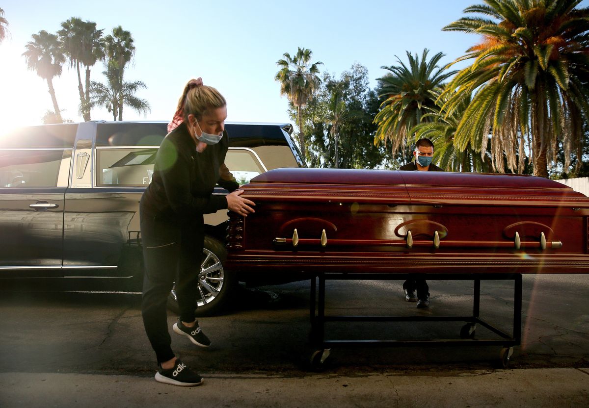 EL CAJON, CALIFORNIA - JANUARY 15: (EDITORIAL USE ONLY) Embalmer and funeral director Kristy Oliver (L) and funeral attendant Sam Deras prepare to load the casket of a person who died after contracting COVID-19 into a hearse at East County Mortuary on January 15, 2021 in El Cajon, California. The mortuary on average was handling about 50 decedents per month but owner Robert Zakar believes they may process closer to 100 in January as California continues to see a spike in coronavirus deaths. The mortuary holds the bodies of those who pass away due to COVID-19 for a minimum of three days before they are processed along with various other COVID-related safety measures.  (Photo by Mario Tama/Getty Images) (Mario Tama/Getty Images)