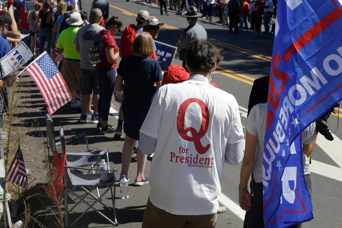 FILE - In this Aug. 20, 2020, file photo, a man in a QAnon T-shirt walks among Trump supporters as they wait for President Donald Trump to arrive and visit Mariotti Building Products in Old Forge, Pa.Experts and former QAnon believers say they have tips for anyone wondering how to talk to people consumed by the conspiracy theory. (AP Photo/Jacqueline Larma, File) (AP Photo/Jacqueline Larm)