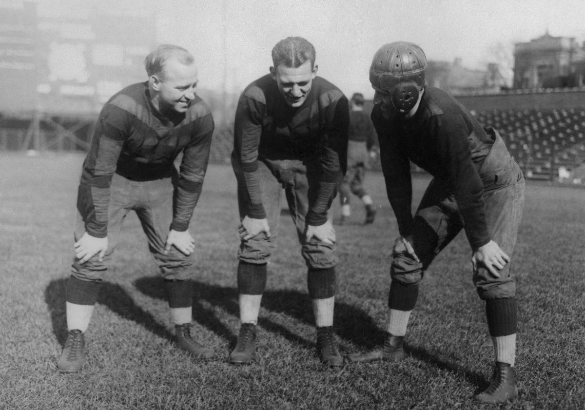 (Original Caption) Red Grange, ace of football, practiced for the first time today with the Bears and this is the first picture of Grange in a professional football uniform. Left to Right: "Dutch" Sternaman, Grange, and George Halas. (Getty Images)