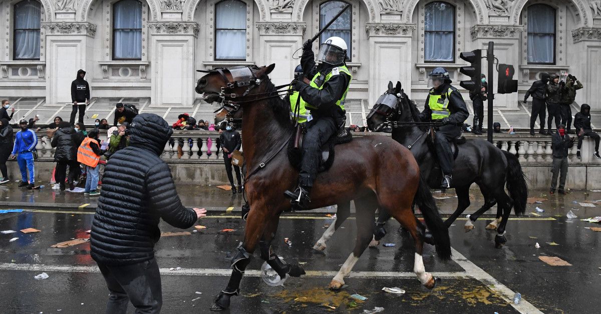 A mounted police officer raises their baton as police horses ride along Whitehall, past the entrance to Downing Street, in an attempt to disperse protestors gathered in central London on June 6, 2020, during a demonstration to show solidarity with the Black Lives Matter movement in the wake of the killing of George Floyd, an unarmed black man who died after a police officer knelt on his neck in Minneapolis. - The United States braced Friday for massive weekend protests against racism and police brutality, as outrage soared over the latest law enforcement abuses against demonstrators that were caught on camera. With protests over last week's police killing of George Floyd, an unarmed black man, surging into a second weekend, President Donald Trump sparked fresh controversy by saying it was a "great day" for Floyd. (Photo by DANIEL LEAL-OLIVAS / AFP) (Photo by DANIEL LEAL-OLIVAS/AFP via Getty Images) (Daniel Leal-Olivas/AFP via Getty Images)