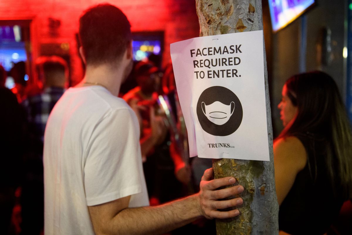Face mask signage is displayed outside the Trunks bar after midnight early Sunday morning on July 18, 2021 in West Hollywood, California. - Wearing a face mask at indoor public establishments will once again be mandatory in Los Angeles County starting at 11:59 pm July 17, 2021 for both vaccinated and unvaccinated people due to a steady increase in Covid-19 infections and hospitalizations, health authorities said. (Photo by Patrick T. FALLON / AFP) (Photo by PATRICK T. FALLON/AFP via Getty Images) (PATRICK T. FALLON / Contributor)