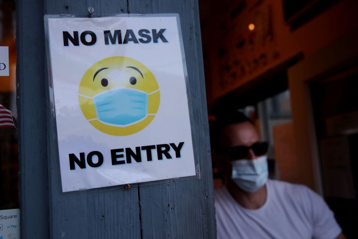 Provincetown, MA - August 6: A man departs Essentials in Provincetown, MA on August 06, 2021, walking past a sign that reads no mask, no entry. (Photo by Craig F. Walker/The Boston Globe via Getty Images) ( Craig F. Walker/The Boston Globe via Getty Images)