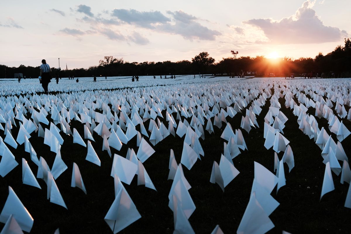 WASHINGTON, DC - SEPTEMBER 18: The sun sets as visitors walk through 'In America: Remember,' a public art installation commemorating all the Americans who have died due to COVID-19 near the Washington Monument on September 18, 2021 in Washington, DC. The concept of artist Suzanne Brennan Firstenberg, the installation includes more than 660,000 small plastic flags, some with personal messages to those who have died, planted in 20 acres of the National Mall. (Photo by Spencer Platt/Getty Images) (Spencer Platt/Getty Images)