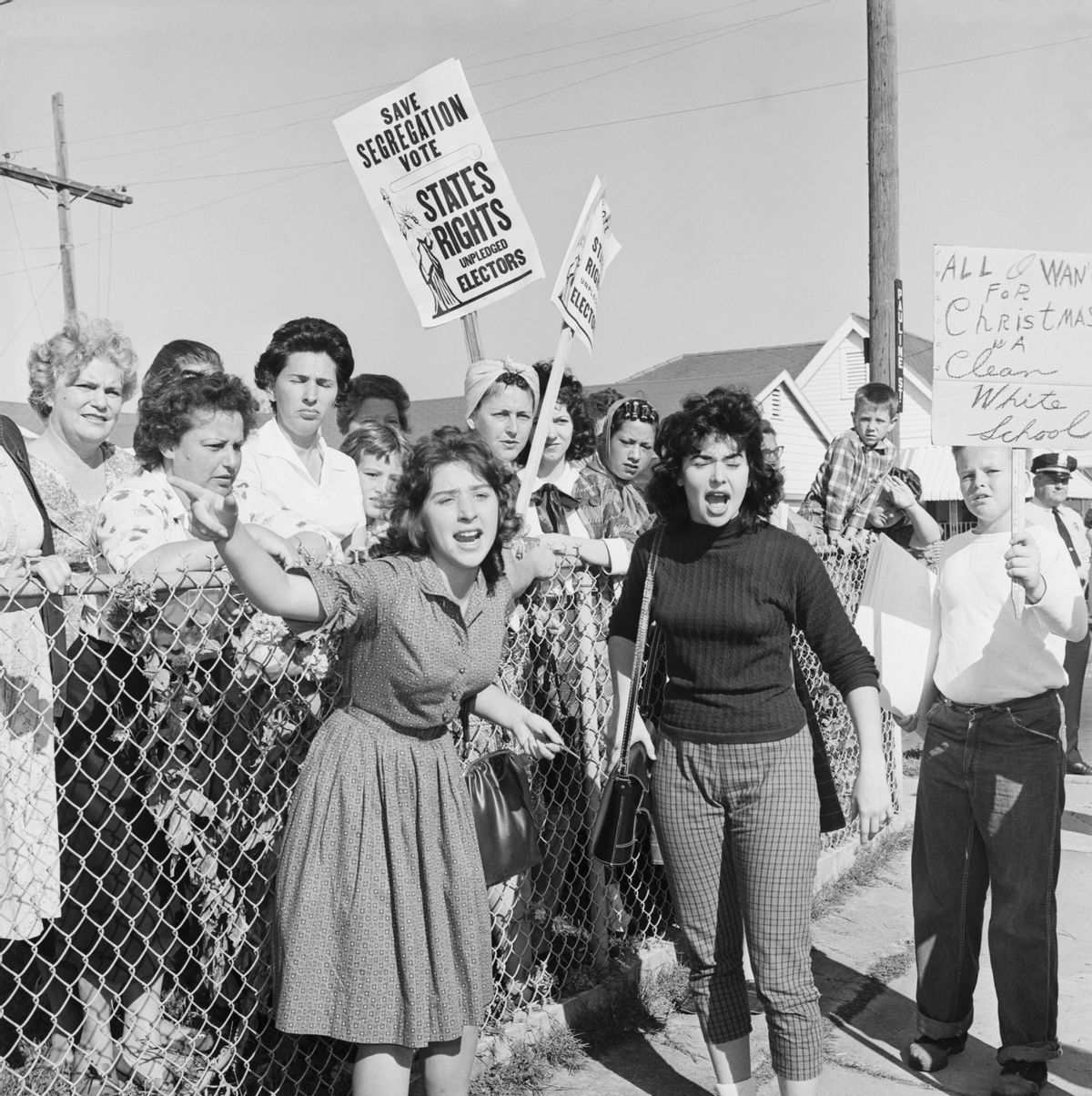Women at William Franz Elementary School yell at police officers during a protest against desegregation at the school, as three black youngsters attended classes at the school for the second day. Some carry signs stating "All I Want For Christmas is a Clean White School" and "Save Segregation Vote, States Rights Pledged Electors" (Bettmann / Contributor)