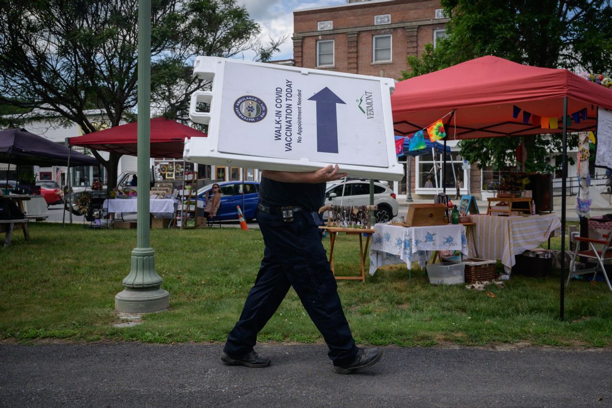 TOPSHOT - An EMT worker carries a sign advertising free vaccinations against Covid-19 at a farmers market in Northfield, Vermont on June 28, 2021. - Vermont -- known for Bernie Sanders, the first Ben and Jerry's and golden fall foliage -- has a new claim to fame: America's most-vaccinated state against Covid-19. Home to red farmhouses and signs warning drivers of moose, the US's second-least populated state recently became the first to partially vaccinate 80 percent of eligible residents. (Photo by Ed JONES / AFP) (Photo by ED JONES/AFP via Getty Images) (ED JONES/AFP via Getty Images)