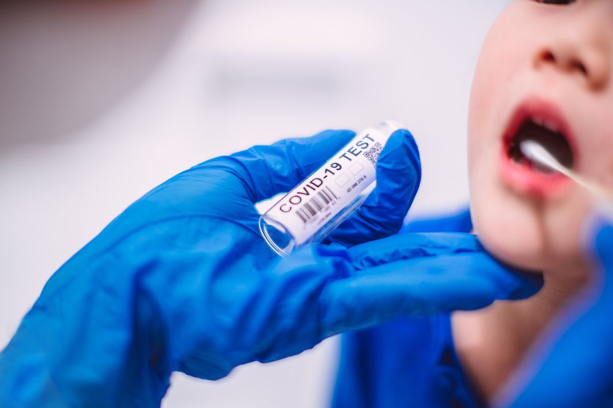 Doctor’s hands in protection gloves putting COVID-19 test swab into kid’s mouth in hospital. (Tang Ming Tung/Getty Images)