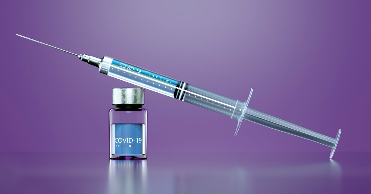 Digital generated image of Syringe with anti COVID-19 vaccine on purple background. (Getty Images)