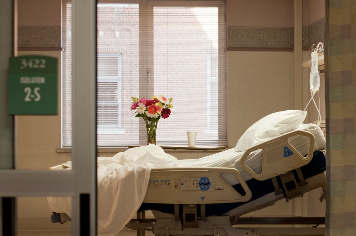 Vacant hospital bed in room with flowers and IV bag. (David Sacks/Getty Images)