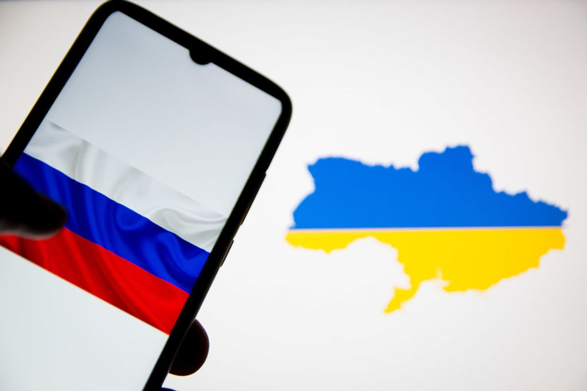 In this photo illustration a flag of Russia seen on a smartphone screen and an Ukraine flag-map in the background in Athens, Greece on February 24, 2022. (Photo by Nikolas Kokovlis/NurPhoto via Getty Images) (Getty Images)