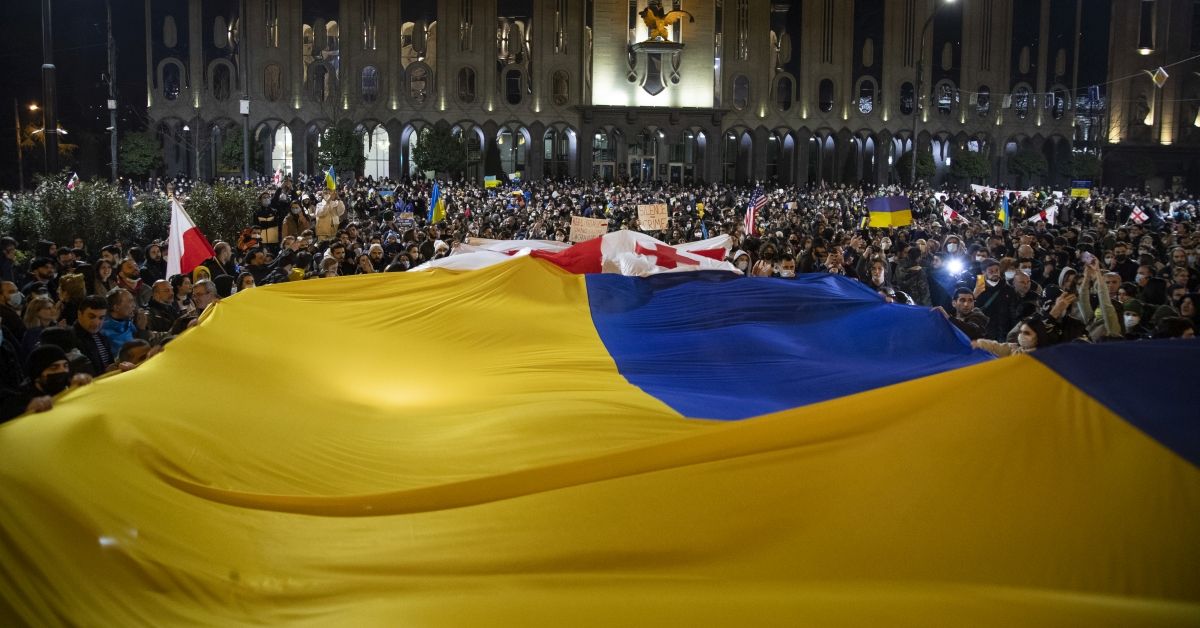 TBILISI, GEORGIA - FEBRUARY 24: Demonstrators wave a large Ukranian flag as Georgians rally in support of Ukraine after Russia began it's military invasion to the country on February 24, 2022 in Tbilisi, Georgia. Overnight, Russia began a large-scale attack on Ukraine, with explosions reported in multiple cities and far outside the restive eastern regions held by Russian-backed rebels. (Photo by Daro Sulakauri/Getty Images) (Daro Sulakauri / Getty Images)