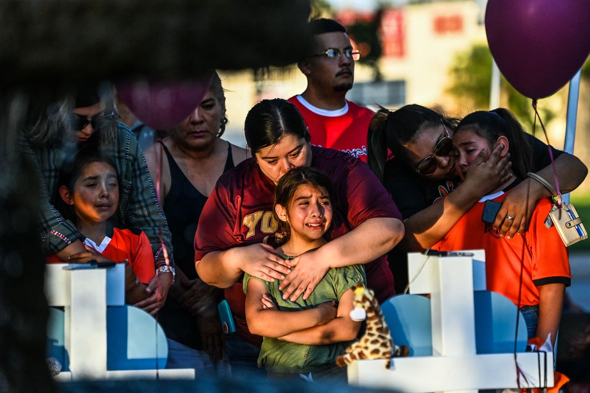 Gabriella Uriegas, a soccer teammate of Tess Mata who died in the shooting, cries while her mother Geneva Uriegas holds her as they visit a makeshift memorial outside the Uvalde County Courthouse in Texas on May 26, 2022. - Texas police faced angry questions May 26, 2022 over why it took an hour to neutralize the gunman who murdered 19 small children and two teachers in Uvalde, as video emerged of desperate parents begging officers to storm the school. (Photo by CHANDAN KHANNA / AFP) (Photo by CHANDAN KHANNA/AFP via Getty Images) (CHANDAN KHANNA/AFP via Getty Images)